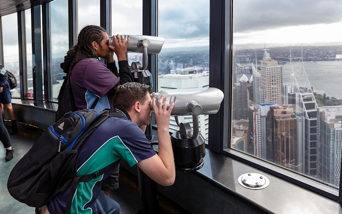 Visitors using binoculars on Sydney Tower Eye observation deck.