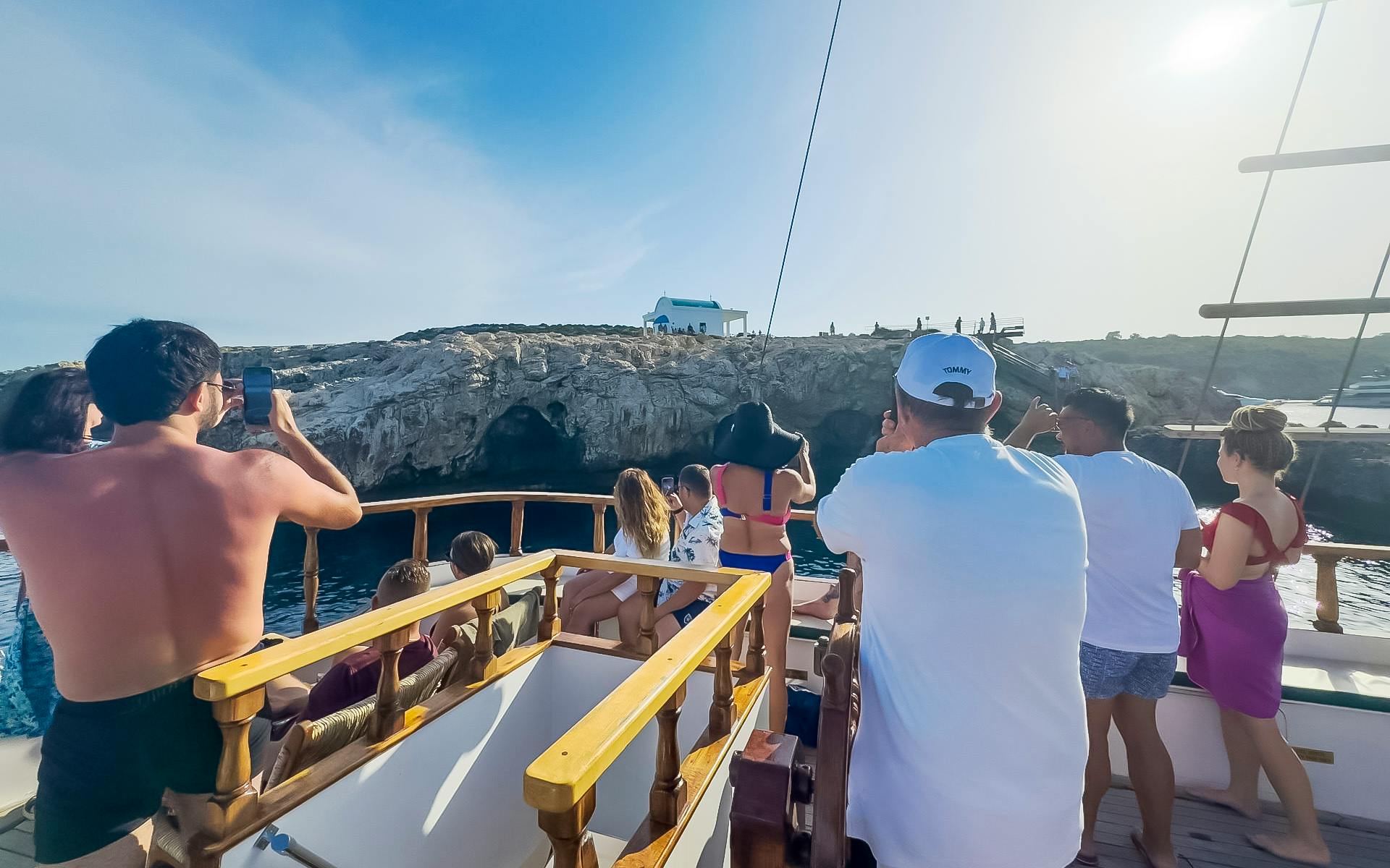 Tourists on a boat enjoying the view of rocky cliffs during a Blue Lagoon sunset cruise near Ayia Napa.