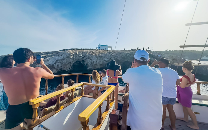 Tourists on a boat enjoying the view of rocky cliffs during a Blue Lagoon sunset cruise near Ayia Napa.