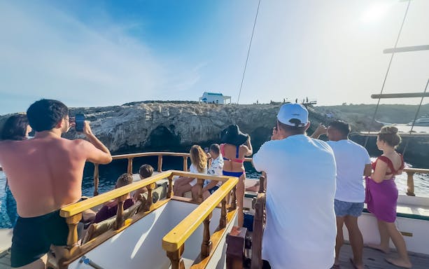 Tourists on a boat enjoying the view of rocky cliffs during a Blue Lagoon sunset cruise near Ayia Napa.