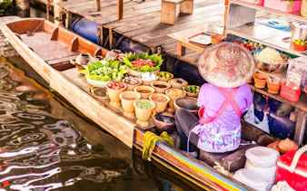 Vendor selling fresh produce from a boat at Damnoen Saduak Floating Market, Thailand.