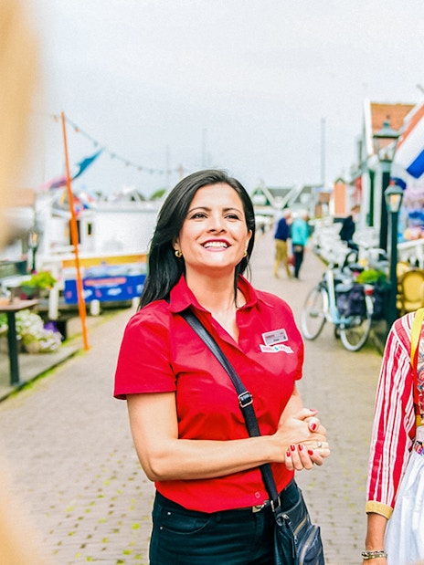 Guide leading a tour in Volendam with traditional Dutch attire in the background.