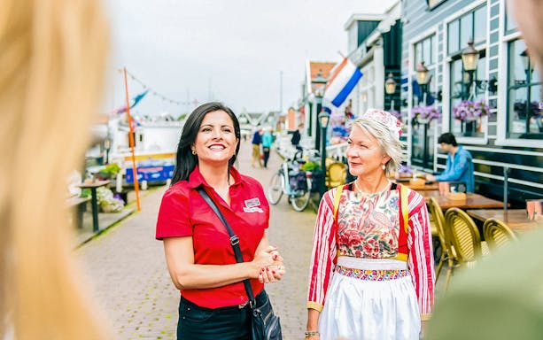 Guide leading a tour in Volendam with traditional Dutch attire in the background.