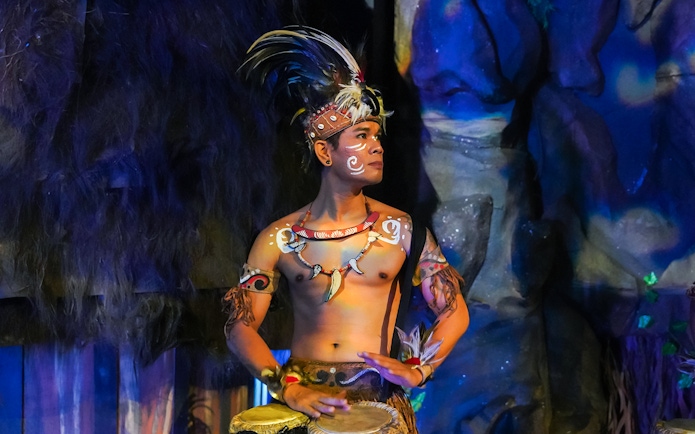 Performer in traditional Indonesian attire playing drums at the Devdan Show, Bali.