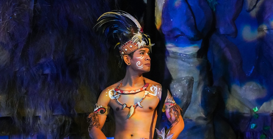 Performer in traditional Indonesian attire playing drums at the Devdan Show, Bali.