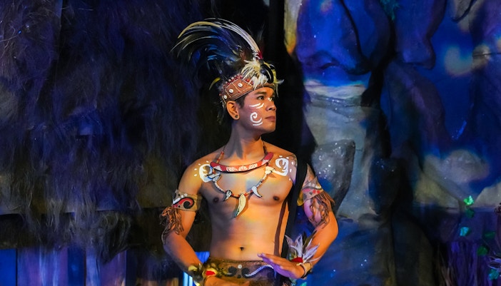 Performer in traditional Indonesian attire playing drums at the Devdan Show, Bali.