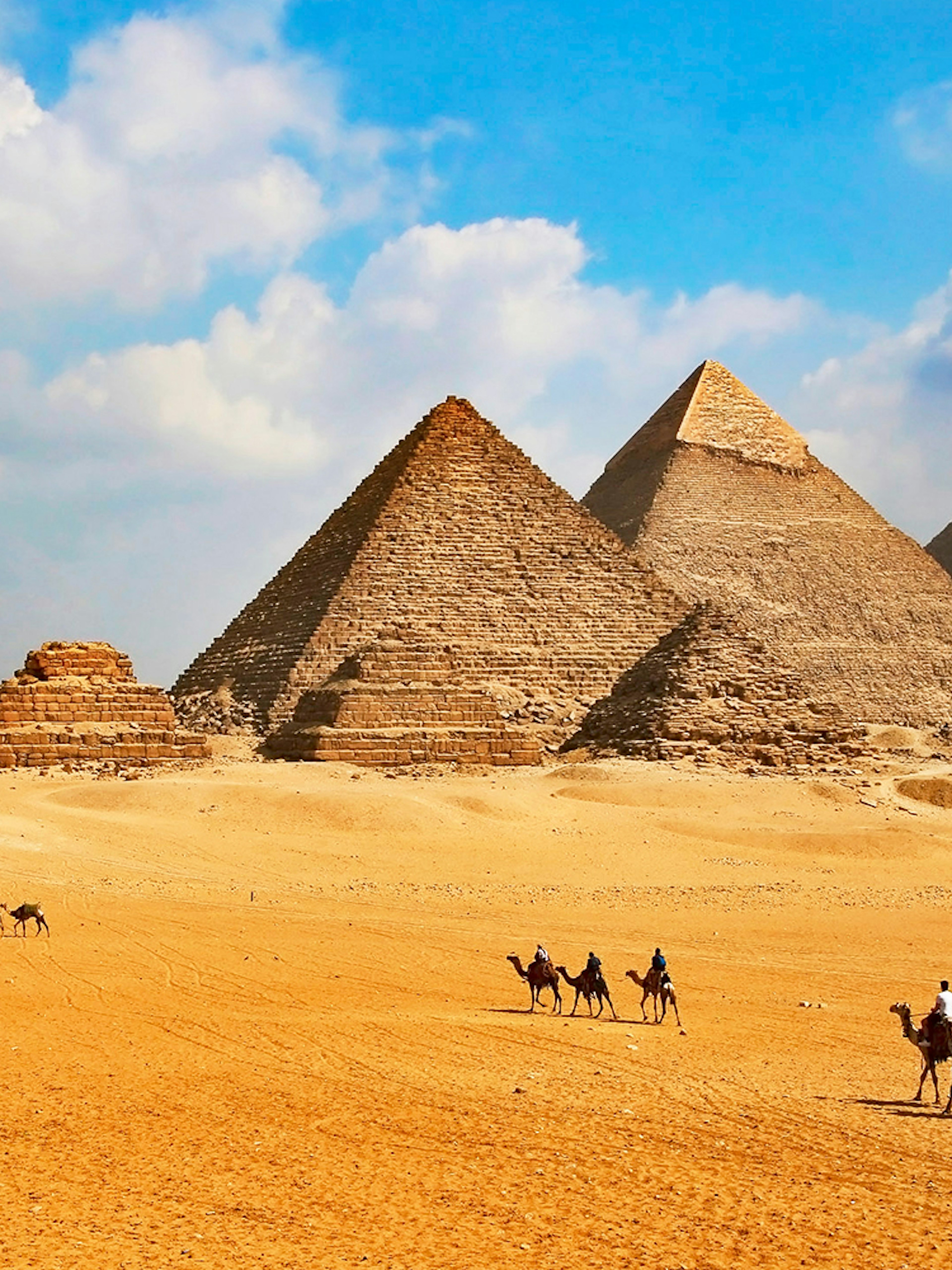 Giza Pyramids with tourists on camels during Cairo half-day tour.
