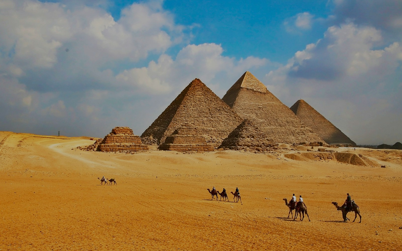 Giza Pyramids with tourists on camels during Cairo half-day tour.