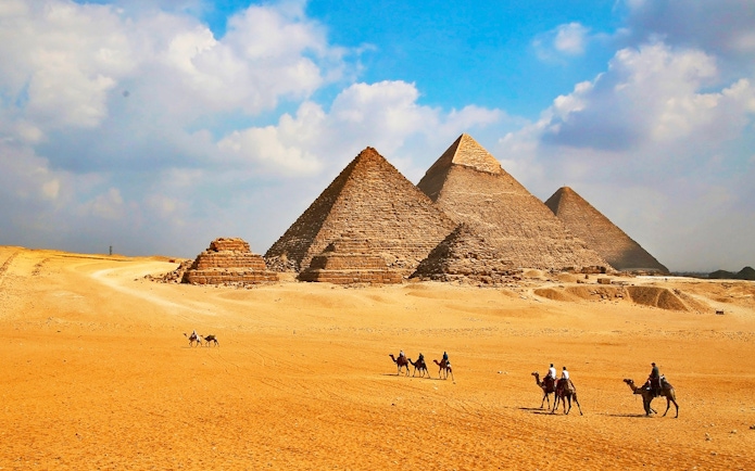 Giza Pyramids with tourists on camels during Cairo half-day tour.