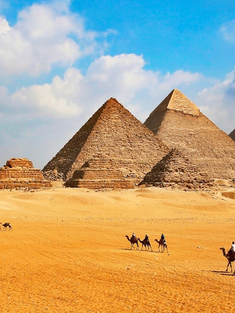 Giza Pyramids with tourists on camels during Cairo half-day tour.