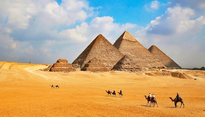 Giza Pyramids with tourists on camels during Cairo half-day tour.