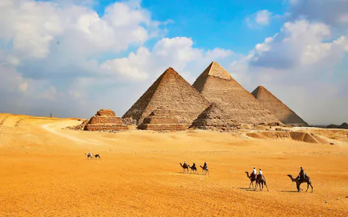 Giza Pyramids with tourists on camels during Cairo half-day tour.