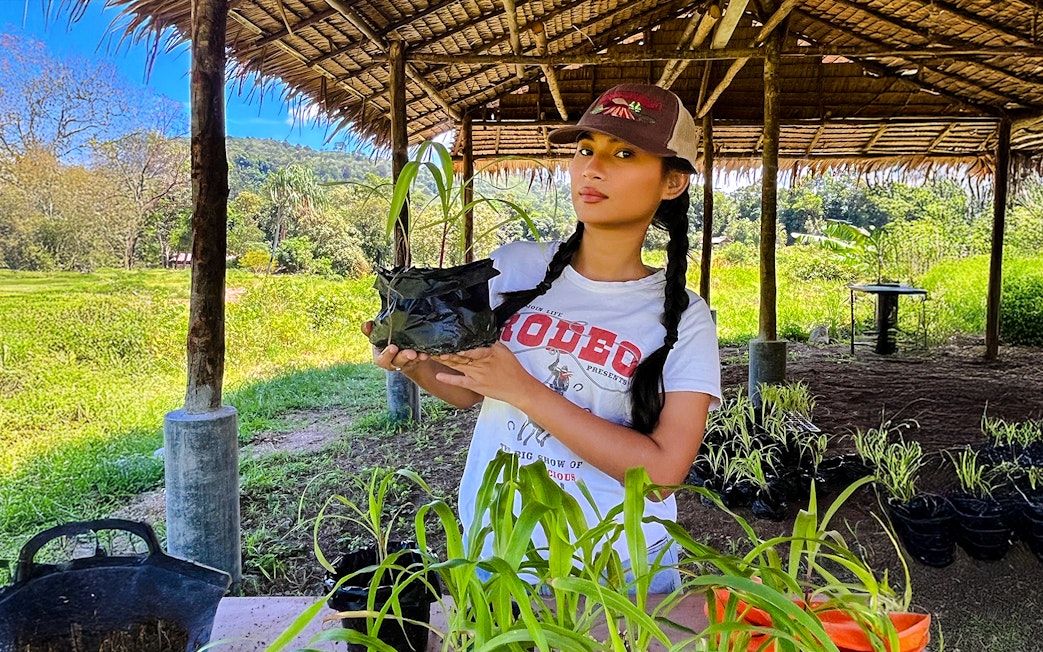 Woman holding corn plant at Bukit Elephant Park.