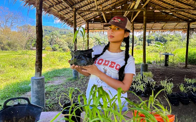 Woman holding corn plant at Bukit Elephant Park.