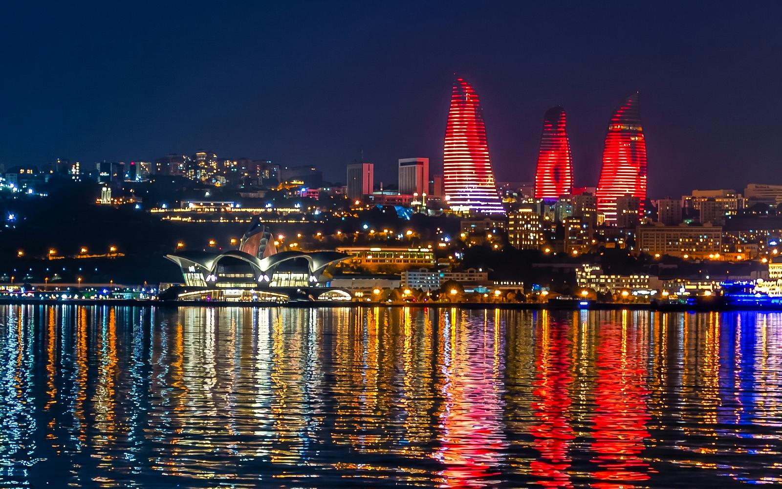 Baku skyline with illuminated Flame Towers reflecting on Caspian Sea during boat tour.