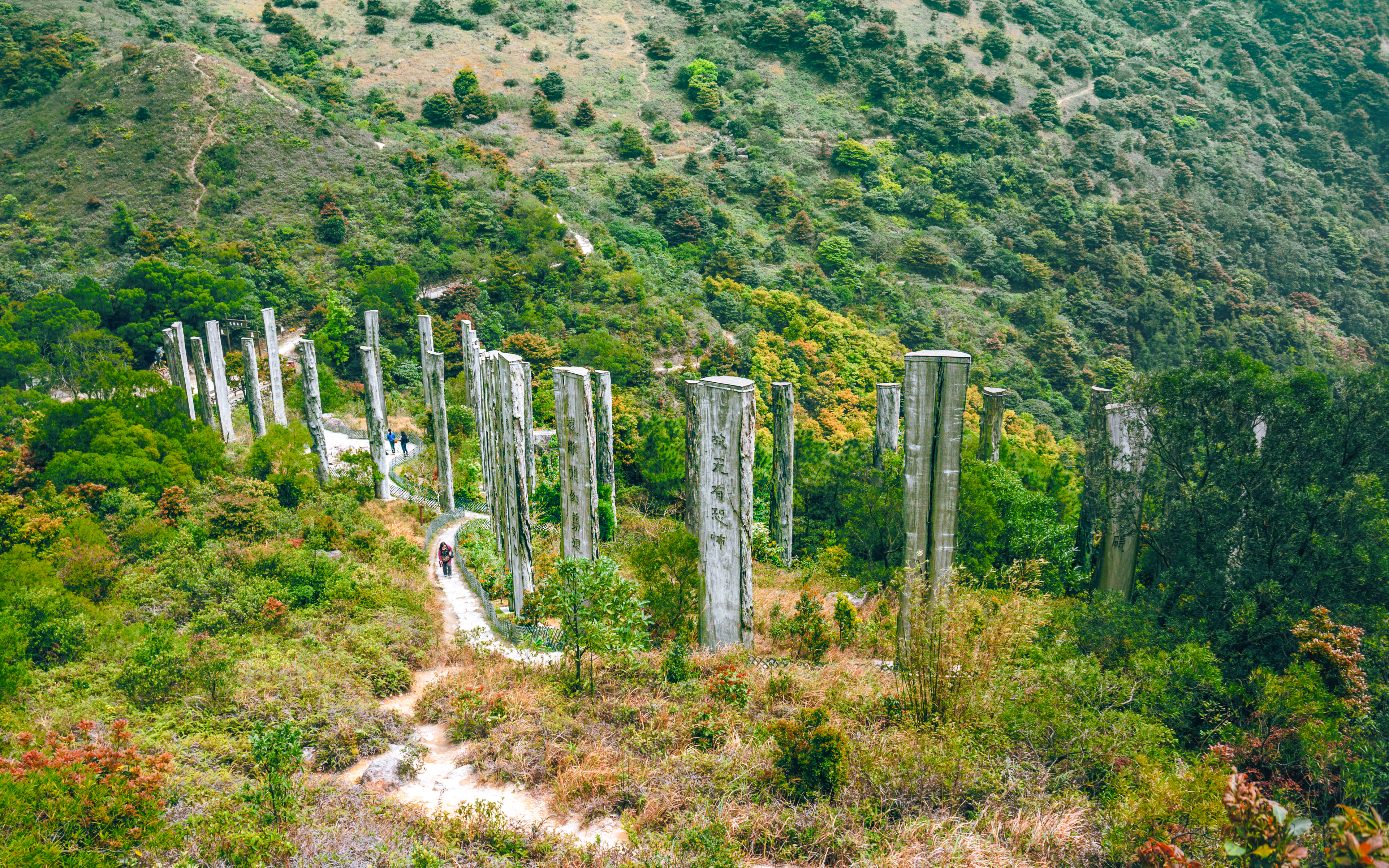 Wisdom Path with wooden pillars on Ngong Ping, Lantau Island, Hong Kong, surrounded by lush hills.