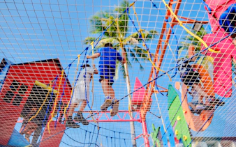 Children climbing a colorful ropes course at a birthday party in Phuket.