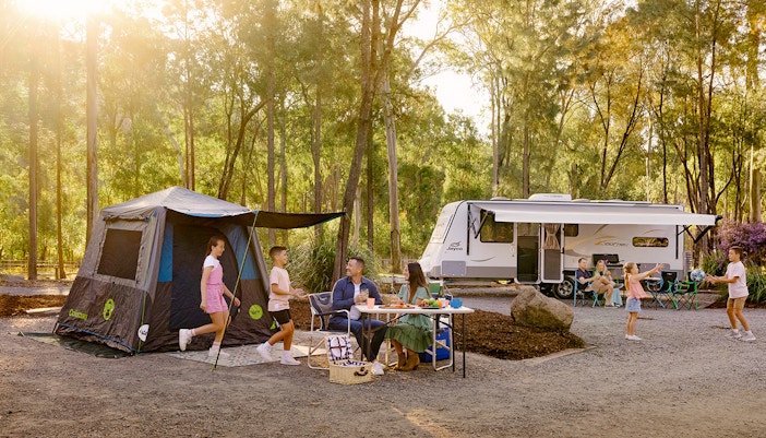 Family camping at Paradise Country with tents and campfire in a scenic forest setting.