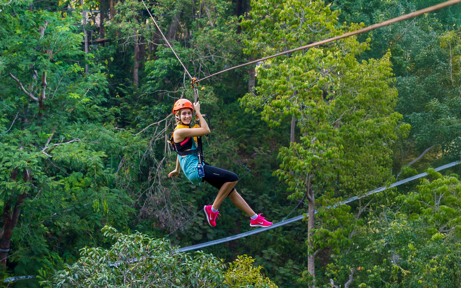 Person ziplining through lush forest at Hanuman World, Phuket.