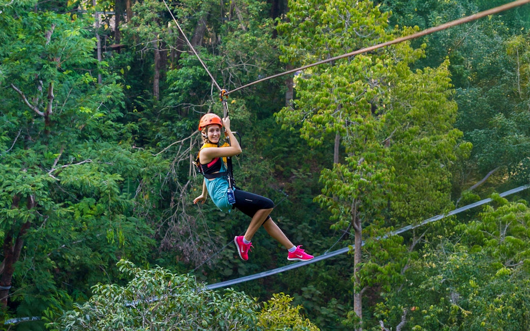 Person ziplining through lush forest at Hanuman World, Phuket.