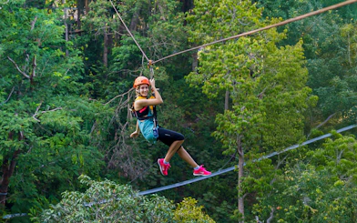 Person ziplining through lush forest at Hanuman World, Phuket.