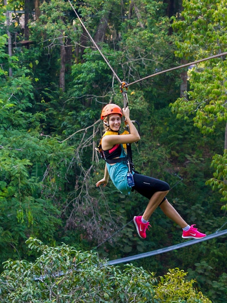 Person ziplining through lush forest at Hanuman World, Phuket.