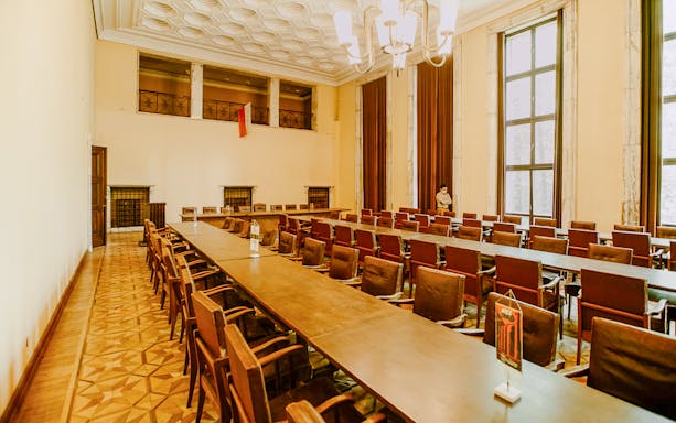 Meeting room in Nowa Huta Steelworks Administration Building, Kraków, with long tables and chairs.