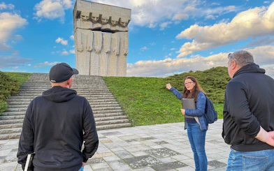 Guide explaining the Plaszow Concentration Camp memorial to visitors in Krakow.