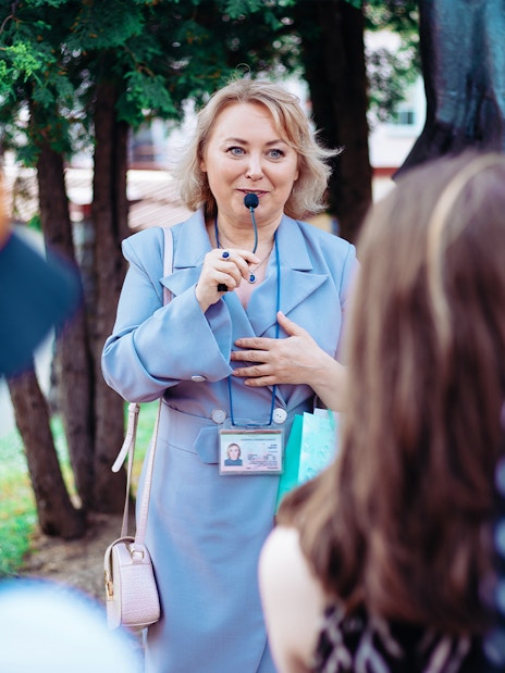 Tour guide speaking to a group outdoors with trees in the background.