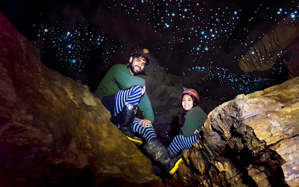 Visitors exploring Waitomo Glowworm Caves with glowing ceiling, New Zealand tour.