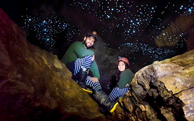 Visitors exploring Waitomo Glowworm Caves with glowing ceiling, New Zealand tour.