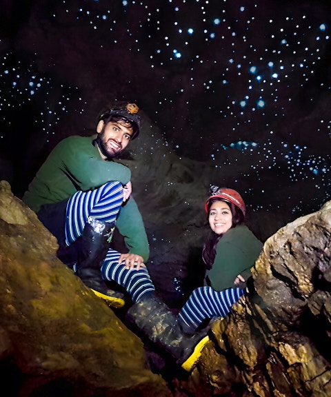 Visitors exploring Waitomo Glowworm Caves with glowing ceiling, New Zealand tour.
