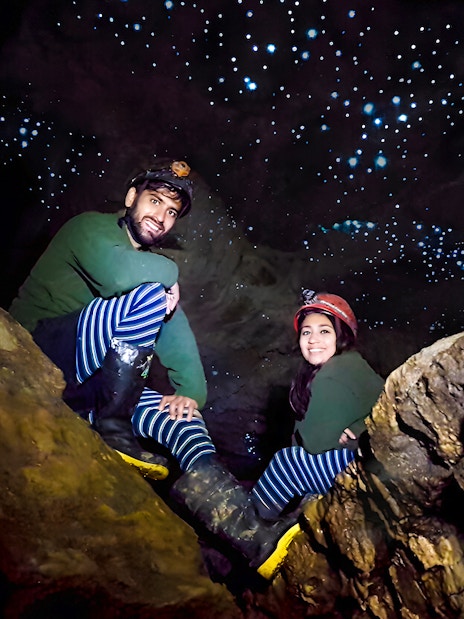 Visitors exploring Waitomo Glowworm Caves with glowing ceiling, New Zealand tour.