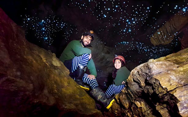 Visitors exploring Waitomo Glowworm Caves with glowing ceiling, New Zealand tour.