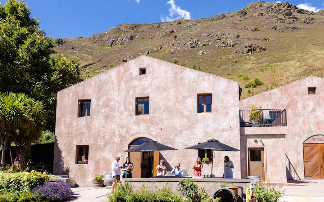Winery visitors enjoying a sunny day at a vineyard in Queenstown.
