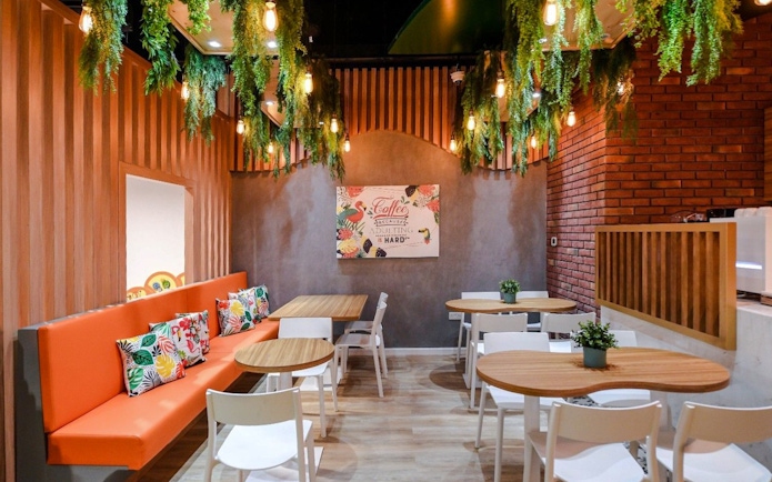 Cafe seating area with orange bench and floral cushions at Orange Wheels, Global Village, Dubai.