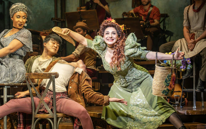 Performers in a lively scene from Hadestown on West End stage.