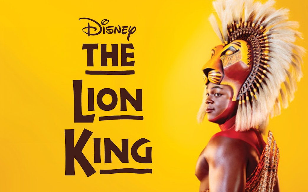 The Lion King performer in costume against a yellow background.