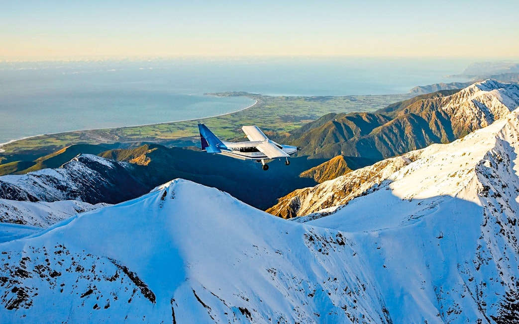 Aerial view of a plane flying over snowy mountains in Kaikoura, New Zealand.