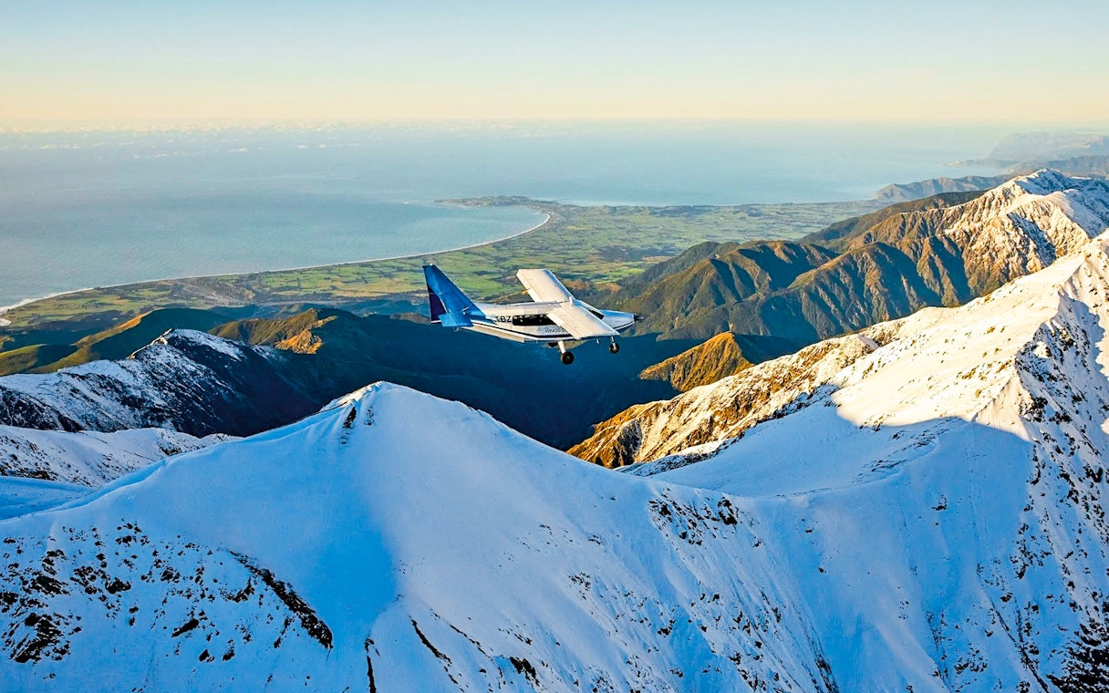 Aerial view of a plane flying over snowy mountains in Kaikoura, New Zealand.