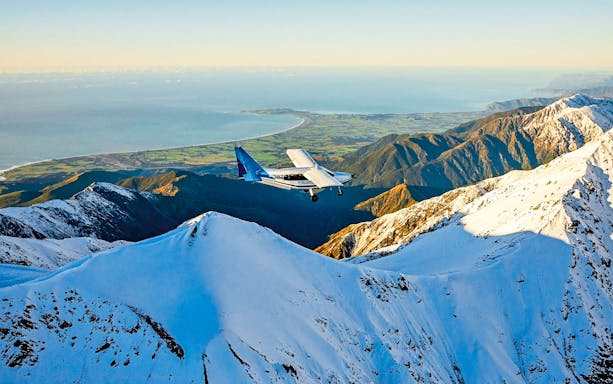 Aerial view of a plane flying over snowy mountains in Kaikoura, New Zealand.