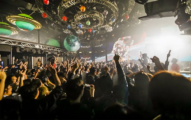 Crowd enjoying music under vibrant lights at WARP Shinjuku Nightclub, Tokyo.