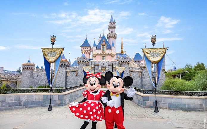 Mickey and Minnie Mouse in front of Sleeping Beauty Castle at Disneyland Park, California.