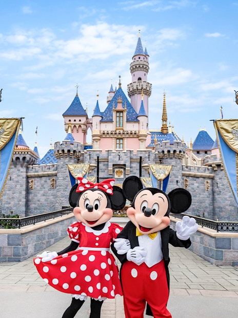Mickey and Minnie Mouse in front of Sleeping Beauty Castle at Disneyland Park, California.
