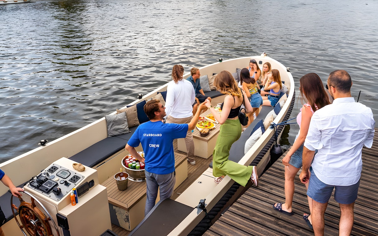 Canal cruise boat with passengers enjoying drinks in Amsterdam's Red Light District.