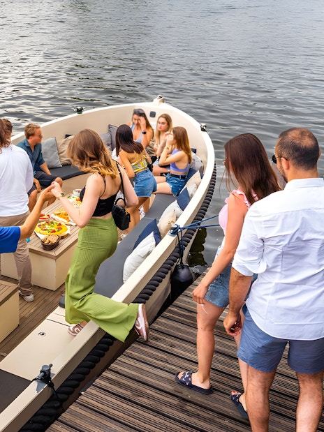 Canal cruise boat with passengers enjoying drinks in Amsterdam's Red Light District.