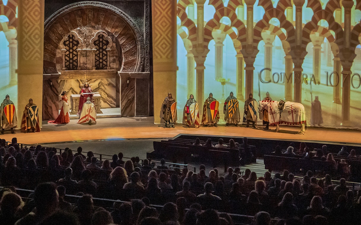 Knights in medieval attire perform on stage at Puy du Fou España, with an audience watching.