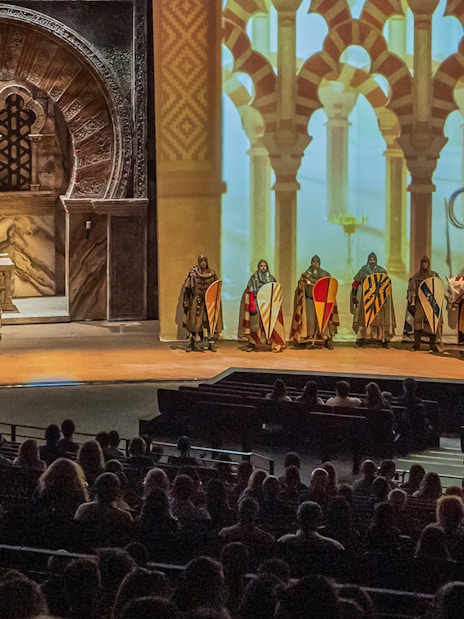 Knights in medieval attire perform on stage at Puy du Fou España, with an audience watching.