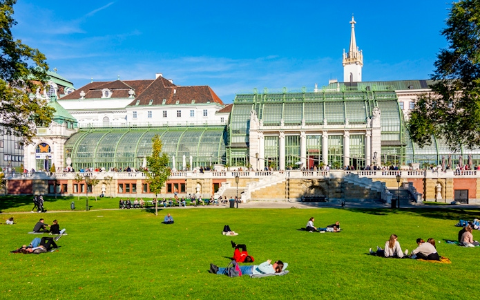 Hofburg Palace gardens with people relaxing on the lawn, Vienna, Austria.