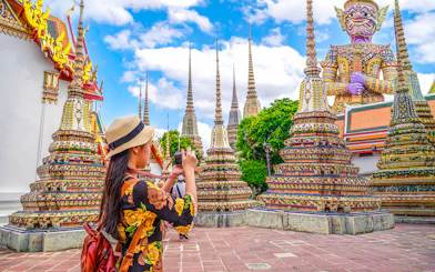 Woman photographing ornate stupas at Wat Pho, Bangkok.